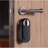 Retrofit smart lock installed on a wooden door beside a lever handle